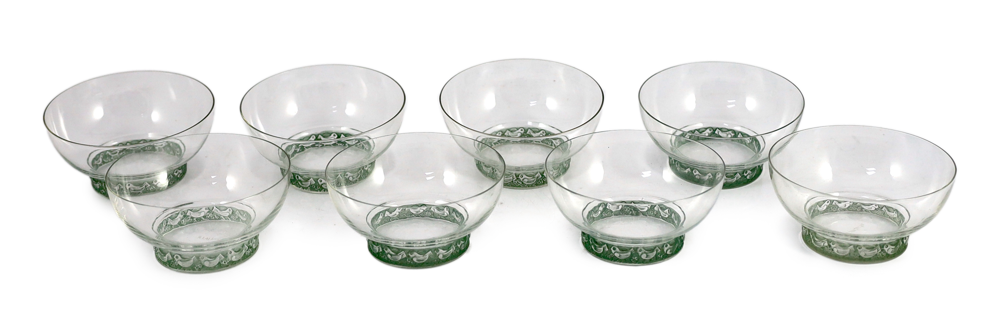 A set of eight R. Lalique Dampierre pattern bowls, model no. 3136, designed 1932, each moulded with a blue stained band of birds around the base, etched mark, 12.1cm diameter one bowl with tiny rim chip